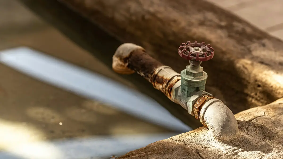 A weathered brass hose spigot on a rough wooden beam - Leak Detection in Mount Prospect
