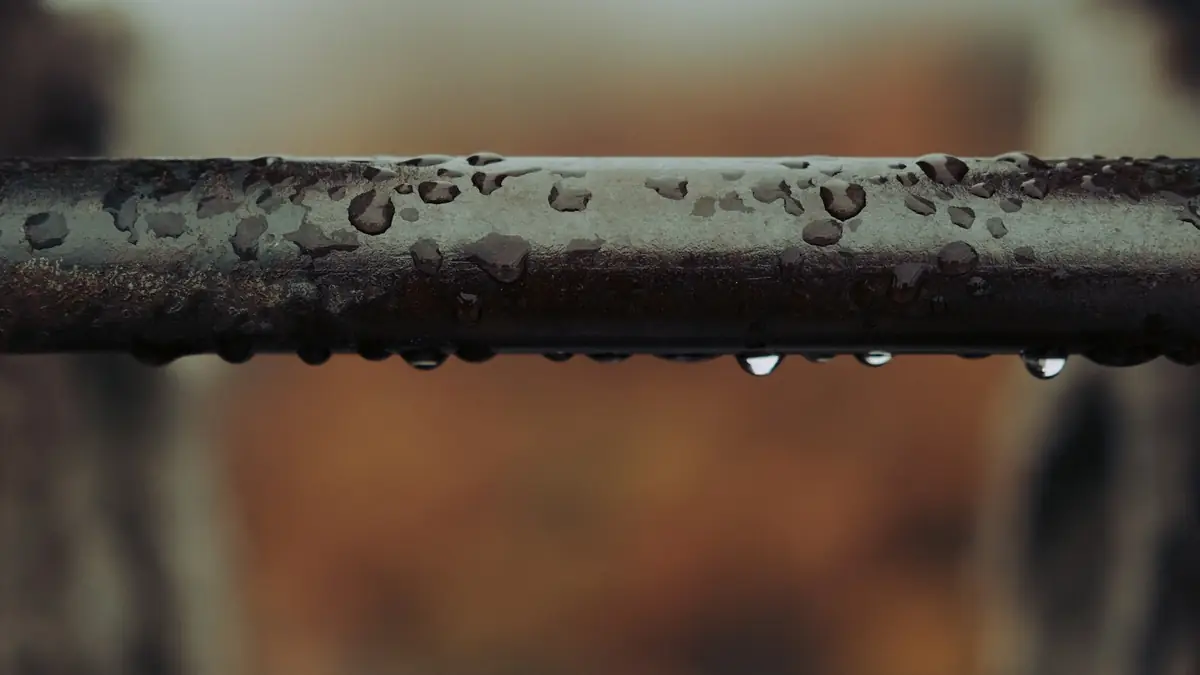 Water droplets hanging from a dark metal pipe - Leak Detection in Cherry Hill